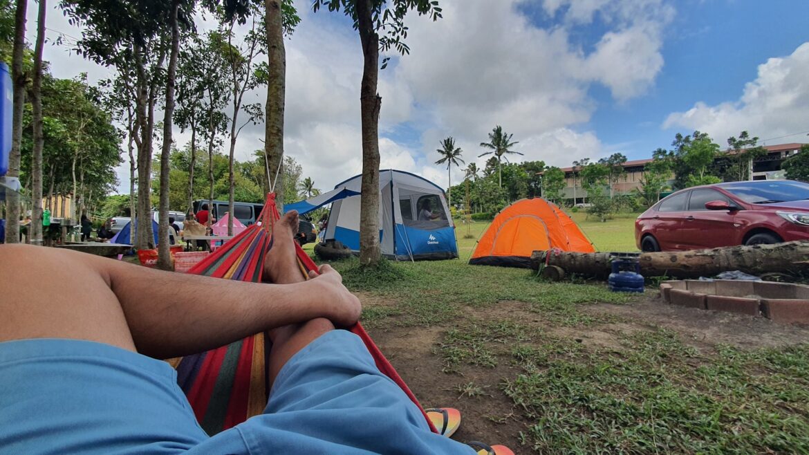 čovek leži u ležaljci ispred kampa, Godišnji odmor