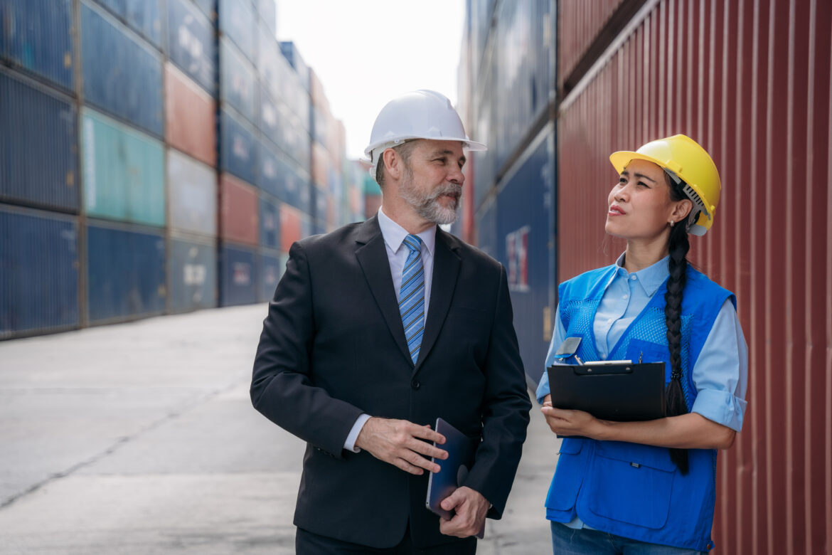 Businessman,  Engineer or foreman talking and checking inventory or task details at container yard warehouse., Logistics concept inside the shipping, import, and export industries. Uredba o trgovini
