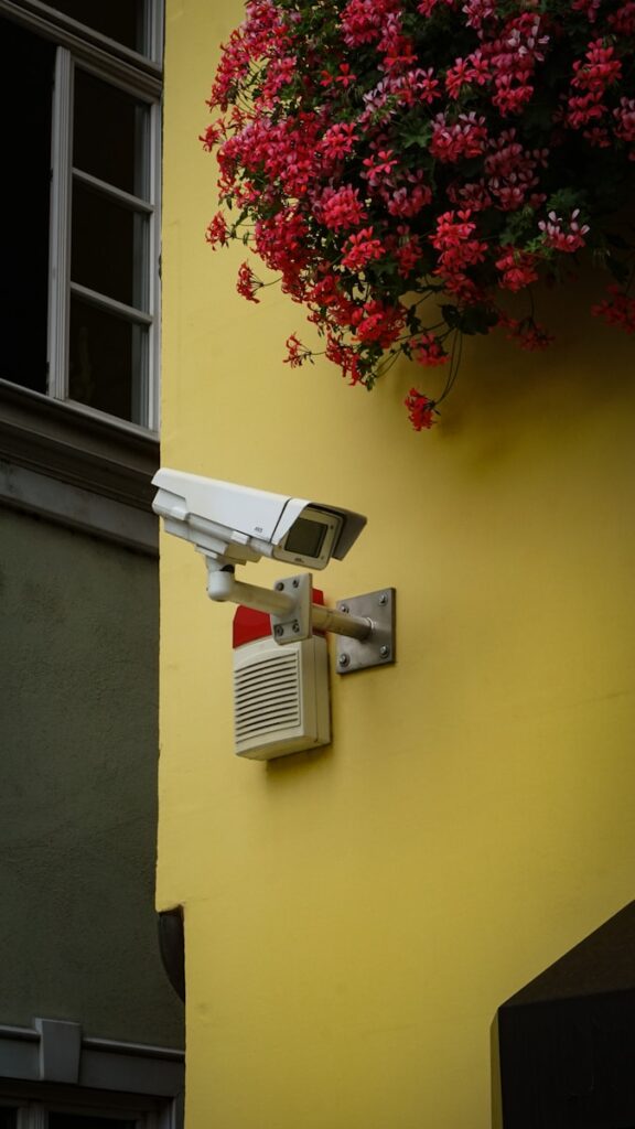 Bela i siva bezbednosna kamera postavljena na žuto obojenom zidu
