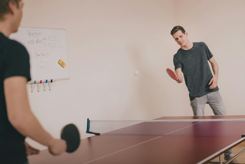 Dva muškarca igraju ping-pong u sobi