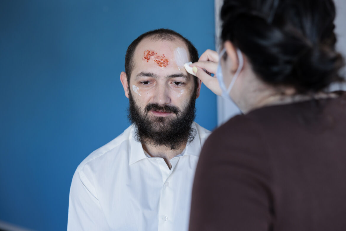 Girlfriend helping man prepare for halloween party, dressing him as zombie Moždani udar