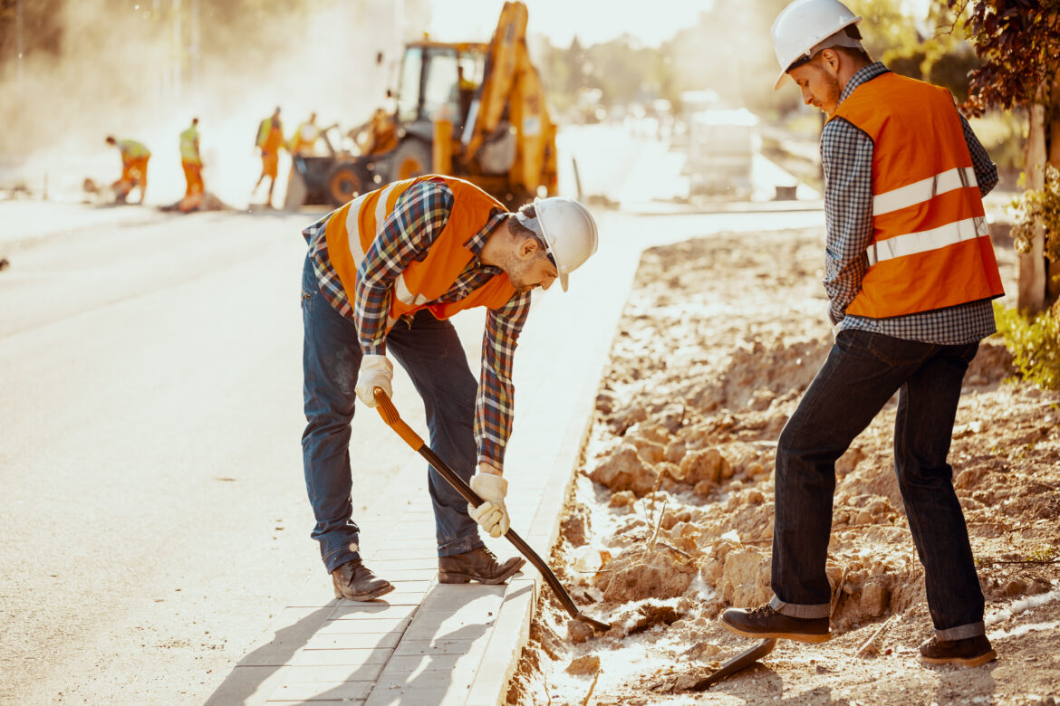 Workers in reflective vests using shovels during carriageway wor Rekonstrukcija ulice